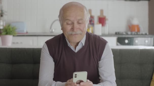 那位老人用智能手机拨通了电话号码 这位老人在家里用手机发短信 80多岁的老人在智能手机上看手机应用程序 短信和新闻 — 图库视频影像