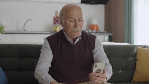 携帯電話で見たメッセージに腹を立てた老人は スマホで見た悪い知らせを読みながら技術を使おうとしている — ストック動画