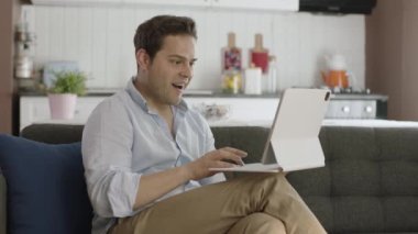 Tablet bilgisayarda çalışan gülümseyen genç adam şaşırmış ve tablet bilgisayar ekranını işaret ediyor. Çevrimiçi rezervasyon hizmeti, uygulama tanıtımı ve reklam konsepti.