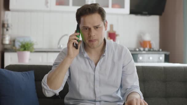 Sinirli Genç Adam Oturma Odasında Cep Telefonuyla Konuşan Biriyle Tartışıyor — Stok video