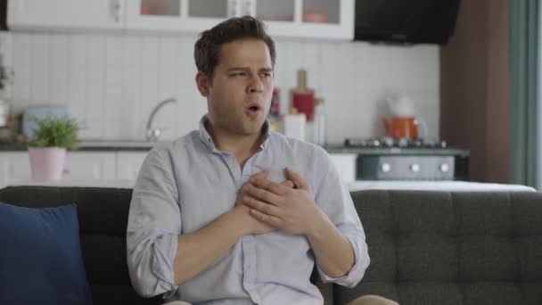 Jovem Sentado Sua Poltrona Casa Experimenta Ataque Cardíaco Repentino Cãibras — Vídeo de Stock