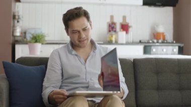 Adam dizüstü bilgisayarını kitap gibi tutuyor. Genç adam sanki dizüstü bilgisayarında kitap okuyormuş gibi sayfaları değiştiriyor. Adam dizüstü bilgisayarında gördüklerine şaşırdı. Gelecek teknolojisi.