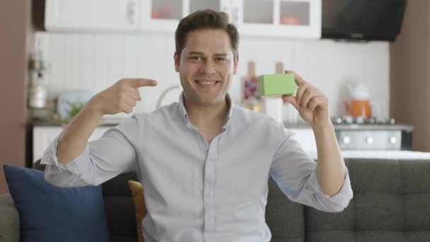 Ung Kaukasisk Stilig Man Håller Något Grönt Visar Produkt Ler — Stockvideo