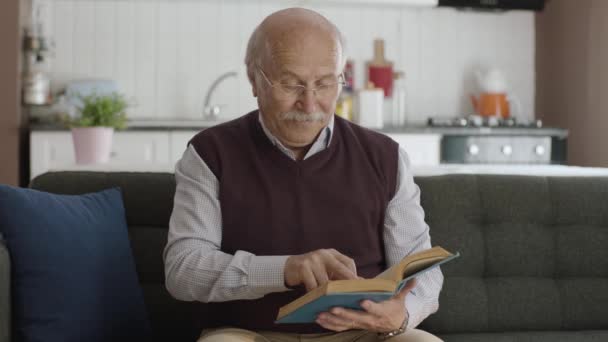 平和な家で本を読んでいる老人は 彼の自由な時間を楽しんでいます 読書への愛の概念 — ストック動画
