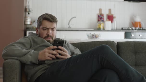 Mladý Muž Který Dívá Svůj Smartphone Zatímco Leží Gauči Používá — Stock video