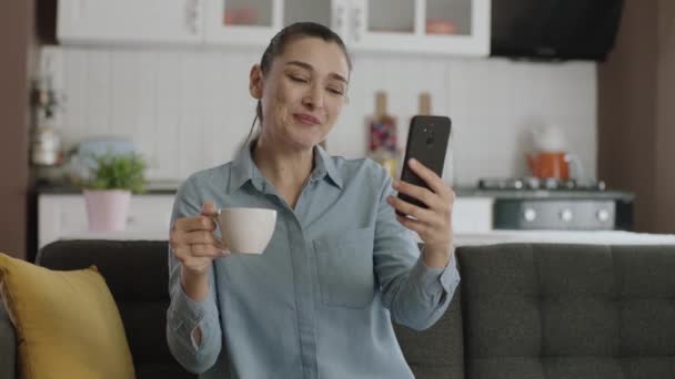Atrakcyjna Młoda Kobieta Pijąca Herbatę Lub Kawę Pomocą Smartfona Siedząc — Wideo stockowe