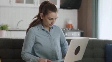 Evdeki kanepede dizüstü bilgisayarda çalışan genç bir kadın. Yeni teknoloji kullanıyor. İş kadını serbest yazar dizüstü bilgisayarla zaman geçiriyor..