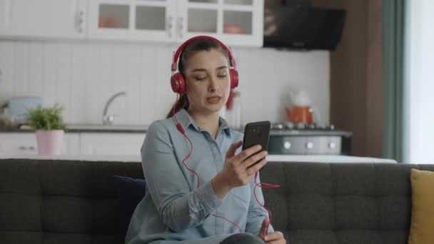 Mujer Sentada Sofá Usando Auriculares Inalámbricos Para Escuchar Música Casa — Vídeo de stock