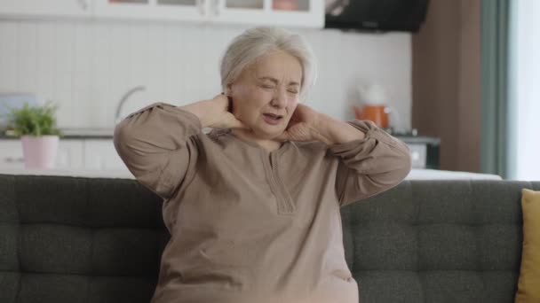 老妇人坐在椅子上 肩头和背都痛 这个女人在按摩她疼痛的地方 有关节问题的老年妇女的画像 — 图库视频影像
