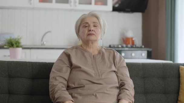 老年妇女感到胸口疼痛 老年妇女坐在家中的扶手椅上 心脏病发作 有心悸的老妇人的画像 急性胸痛 心脏病发作 — 图库视频影像