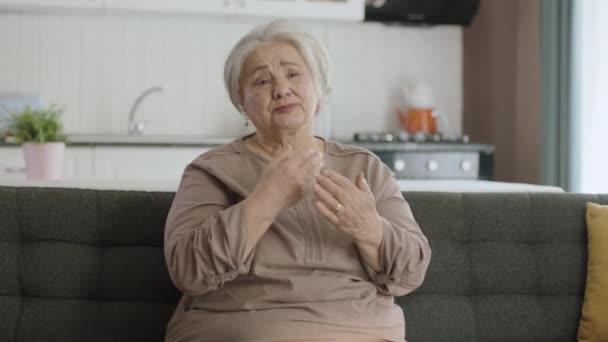 老妇人听到这个消息很不高兴 孤独的老妇人一个人坐在家里的沙发上 不幸老妇人的画像 — 图库视频影像