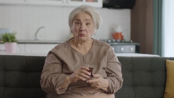 Šťastná Stará Žena Sleduje Zajímavý Film Televizi Zatímco Pije Čaj — Stock video