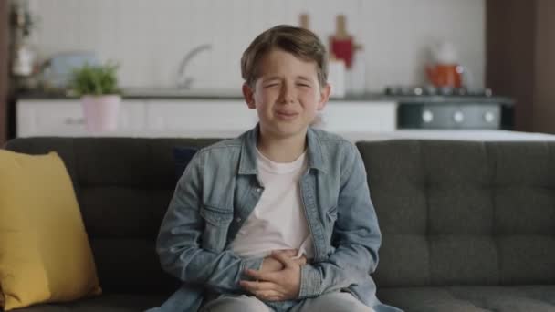 Μικρό Αγόρι Που Υποφέρει Από Στομαχόπονο Ενώ Κάθεται Στον Καναπέ — Αρχείο Βίντεο
