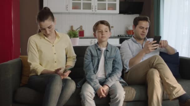 由于需要父母的关注 小男孩厌倦了他那沉迷于科技的父母的困境 一对沉迷于科技的夫妇在智能手机上看他们的社交媒体账户 — 图库视频影像