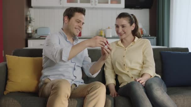 一个年轻人送给他的女朋友一个漂亮的戒指作为情人节礼物 这个年轻人在家里向女朋友求婚戒指 年轻夫妇快乐地拥抱在一起 — 图库视频影像