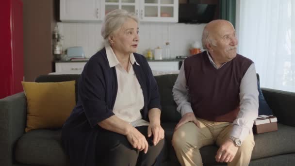 Ώριμο Ηλικιωμένο Ζευγάρι Που Κάθεται Στον Καναπέ Στο Σαλόνι Ευτυχισμένο — Αρχείο Βίντεο
