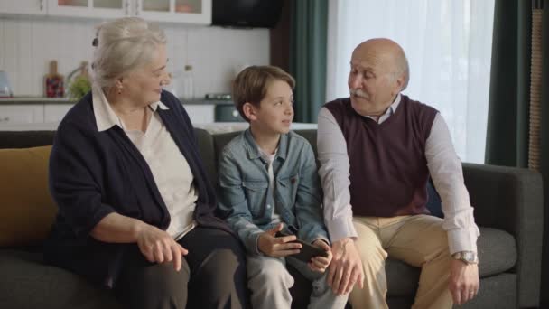 Szczęśliwa Para Starców Siedzi Kanapie Rozmawia Swoim Wnukiem Mały Chłopiec — Wideo stockowe