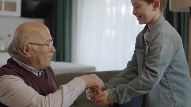 Jongen Die Snoep Kom Aanbiedt Aan Zijn Oude Grootvader Kleine — Stockvideo