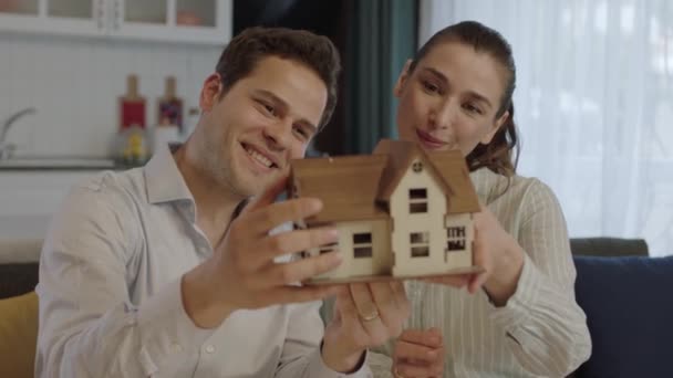 若い夫婦は 購入したばかりの家や賃貸した家のモデルを調べ 新しい家の計画やモデルを手で見て幸せなカップル 新工事 — ストック動画
