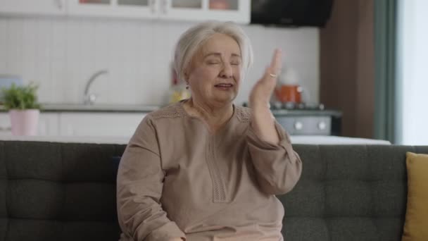 老年漂亮的退休女性肖像画的概念 老年女性一个人在客厅舒适的沙发上放松 女人在她现代的家度过她的闲暇时间 — 图库视频影像
