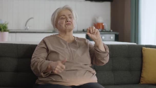 一位白发苍苍的老妇人指着客厅里的一片药丸 她指出手中的药是完美的 快乐的老妇人表现出医疗保健 疾病治疗 维生素 — 图库视频影像