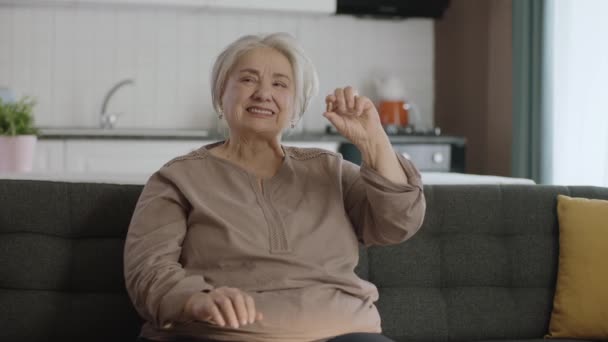 一位白发苍苍的老妇人坐在客厅的沙发上 把药丸展示给大家看 奶奶放弃了大拇指的标志 — 图库视频影像