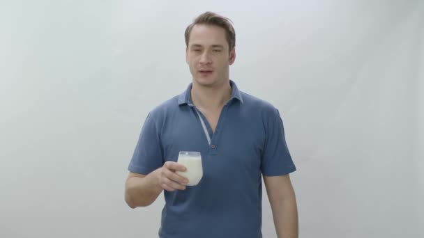 白い背景にミルクのガラスの若い男 男は牛乳を飲むことは健康であることを示しています カルシウムの力 — ストック動画