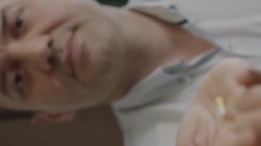 The hand of the person holding the pill towards the camera. The man holds a yellow pill in his palm towards the person being treated towards the camera. Portrait of human holding capsule pill.