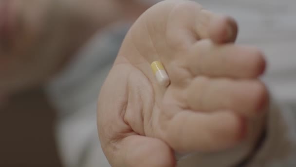カメラに向かって薬を持っている人の手 男はカメラに向かって扱われている人に向かって彼の手のひらに黄色の錠剤を保持しています カプセル人間像 — ストック動画