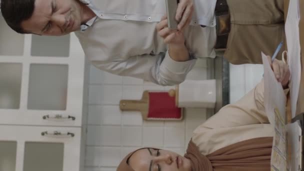 一对穆斯林年轻夫妇在家里的厨房里检查付款单 他们管理家庭预算 讨论花钱问题 支付问题 他们计算双重账单 他们会感到压力 垂直视频 — 图库视频影像