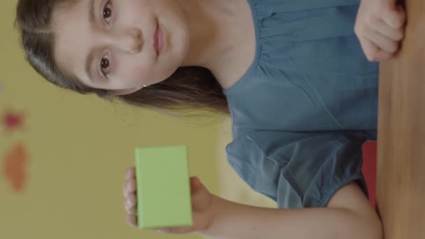 Dziewczyna Trzyma Zielone Pudełko Stole Przedszkolu Pokazując Produkt Uśmiechając Się — Wideo stockowe