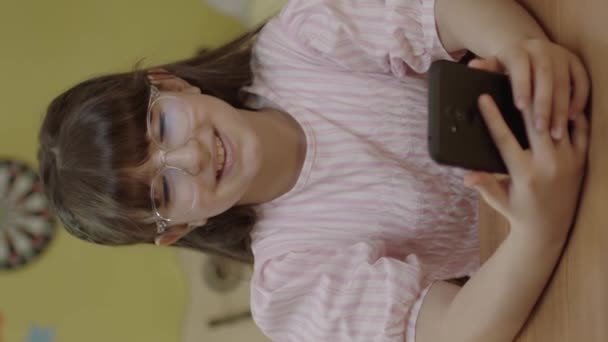 귀여운 소녀가 스마트폰으로 온라인 게임을 하면서 새로운 기술을 사용하고 있습니다 — 비디오