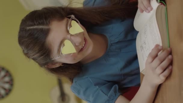 Küçük Bir Kız Gözlüklerinde Kalp Şeklinde Kağıtlarla Odasında Kitap Okuyor — Stok video