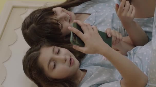 子供たちは技術的なコミュニケーションツール タブレットコンピュータでインターネットをサーフィンしています 女の子はベッドでオンラインレッスンに耳を傾け ビデオを見て ゲームをプレイする垂直ビデオ — ストック動画