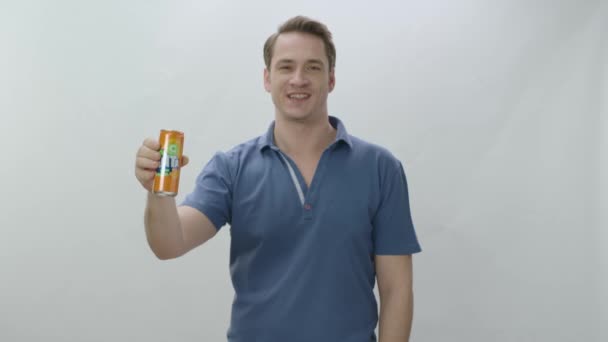 男は金属ボトルからファンタを飲む 若い男はソーダを飲んで クールオフに満足している スローモーションビデオ 白地に隔離された屋内スタジオ — ストック動画