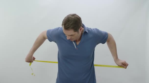 腰と腹をテープで測定する男白い背景に隔離されたテープメジャーで腰サイズを測定する若い男 超過重量だ — ストック動画