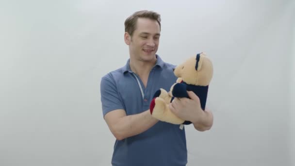 年轻男子抱着一只孤立在白色背景上的泰迪熊 年轻男子抱着一只毛茸茸的泰迪熊 情人节 母亲节的概念 — 图库视频影像