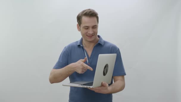 白い背景にノートパソコンを持っている孤立した若い男 ノートパソコン内の指で指している若い男 創造的な人々は広告スペースにほしいものは何でも置くことができる — ストック動画
