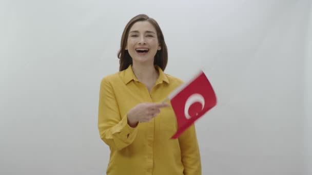 快乐的年轻女子在白色的背景上飘扬着土耳其国旗 微笑的年轻女子在白色背景下与土耳其国旗共庆 庆祝国家的特殊日 — 图库视频影像