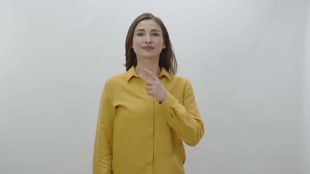 女人笑着看着白色背景上的相机 穿着黄色衬衫的漂亮女人的画像 — 图库视频影像