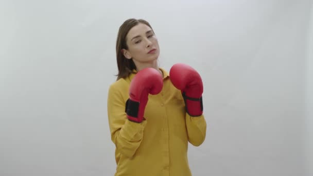 应对商业生活中的困难 年轻女人戴着拳击手套 背景是白色的 年轻女子带着拳击手套 紧张地冲刺相机进行运动 强壮的女人像 — 图库视频影像