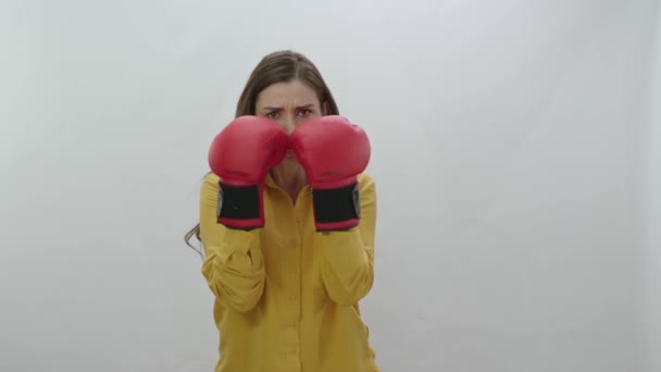 应对商业生活中的困难 年轻女人戴着拳击手套 背景是白色的 年轻女子带着拳击手套 紧张地冲刺相机进行运动 强壮的女人像 — 图库视频影像