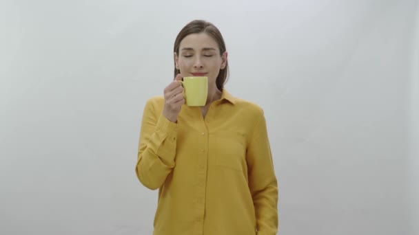 コーヒー 黒または緑のお茶を飲む若い女性の文字の肖像画 若い健康な女性は 白の背景に隔離されたコーヒーや紅茶のカップを嗅ぎ カメラに向ける — ストック動画
