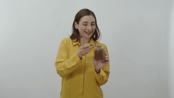 若い女性のキャラクターの肖像画は スプーンでガラス瓶から彼女のお気に入りのチョコレートを食べています — ストック動画