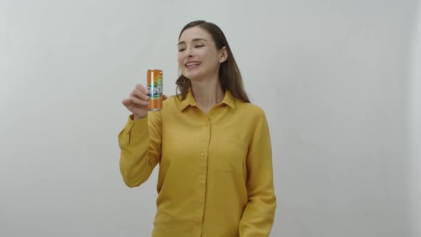 一个年轻女子喝着罐装芬达的人物肖像 快乐的年轻女子和她最喜欢的芬达在白色背景下隔离了起来 — 图库视频影像