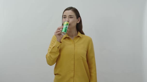 一个年轻女子用铁罐喝雪碧的人物肖像 快乐的年轻女人和她最喜欢的雪碧躲在白色的背景下 — 图库视频影像