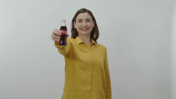 ガラス瓶からコカ コーラを飲む若い女性のキャラクターポートレート 幸せな若いです女性冷却オフとともに彼女のお気に入りコカ コーラ隔離された上の白い背景 — ストック動画