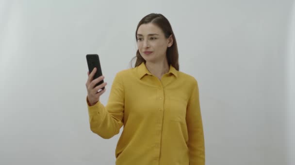 隔離された背景の上に立っている間緑の画面を持つスマートフォンを示す魅力的な若い女性 緑の画面を持つスマートフォンを指して楽しい女性 — ストック動画