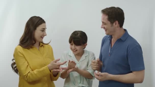 白い背景の幸せな家族 小さな女の子は両親と岩はさみ紙ゲームをしています 幸せな両親 彼らの娘と楽しい家族 理想的で幸せな家族の肖像画 — ストック動画