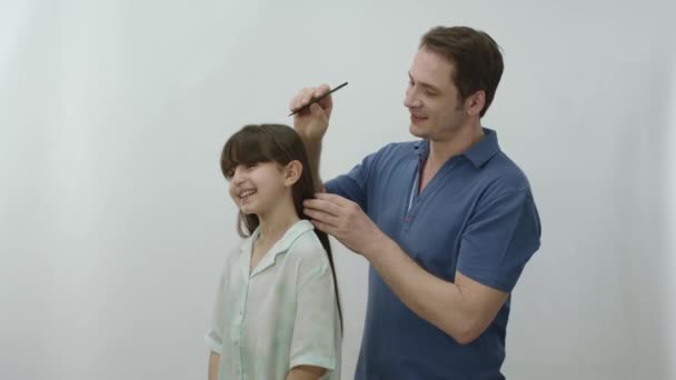 Beyaz Arka Planda Genç Bir Baba Küçük Kızının Saçını Tarıyor — Stok video